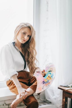 Odada poz veren genç ve güzel sanatçı kadın