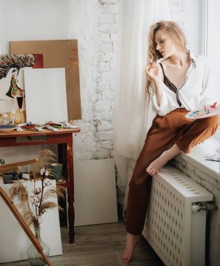 Odada poz veren genç ve güzel sanatçı kadın