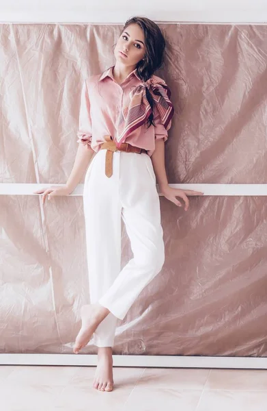 美丽的年轻女子在粉红色上衣和白色裤子摆姿势 — 图库照片
