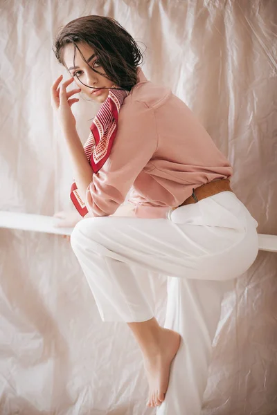 美丽的年轻女子在粉红色上衣和白色裤子摆姿势 — 图库照片
