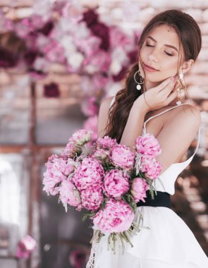  evde poz makyaj ve pembe çiçekler ile güzel genç kadın