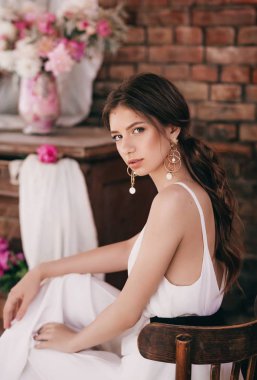  evde poz makyaj ve pembe çiçekler ile güzel genç kadın