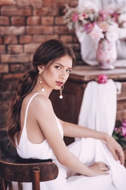  evde poz makyaj ve pembe çiçekler ile güzel genç kadın