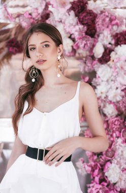  evde poz makyaj ve pembe çiçekler ile güzel genç kadın