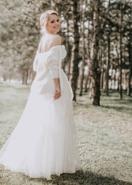 Parkta poz beyaz gelinlikle güzel genç gelin  