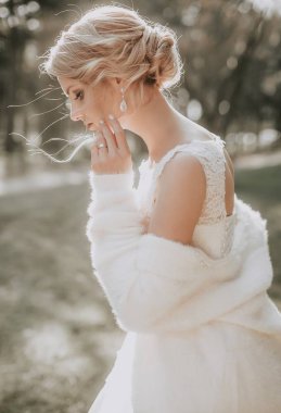 Parkta poz beyaz gelinlikle güzel genç gelin  