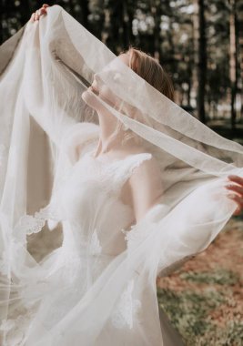 Parkta poz beyaz gelinlikle güzel genç gelin  