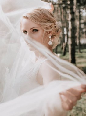 Parkta poz beyaz gelinlikle güzel genç gelin  