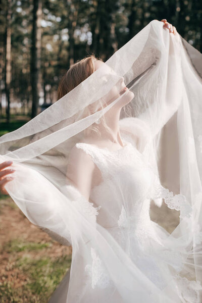 Beautiful Young Bride in White Wedding Dress Posing in Park