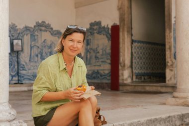 Gen Z orta yaşlı kadın Lizbon 'da fırın yakınlarında Pastel de Nata adında Portekiz yumurtalı tart tatlısı deniyor. Yalnız turizm ve seyahat. Bir serinin parçası