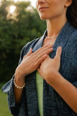 Kadın halka açık bir parkta yoga ve meditasyon yapıyor, gözleri kapalı rahatlıyor. Dikkatli meditasyon konsepti. Sağlıklı olmak. Odak bulanıklığı ve gürültü etkisi yok. Dizinin bir parçası.