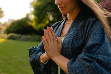 Kadın halka açık bir parkta yoga ve meditasyon yapıyor, gözleri kapalı rahatlıyor. Dikkatli meditasyon konsepti. Sağlıklı olmak. Odak bulanıklığı ve gürültü etkisi yok. Dizinin bir parçası.