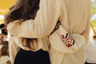 Close-up of Ukrainian traditional costume embroidered vyshyvanka blouse, woven belt kraika, folk jewelry. Ethnic festive clothing, national outfit details, cultural heritage. Part of the series.