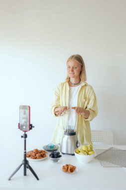 Orta yaşlı bir kadın ev yapımı meyve derisi hazırlıyor, sağlıklı atıştırmalıklar için mutfağında taze meyve dilimliyor. Organik ikramlar ve doğal yaşam üzerine bir serinin parçası. Kullanıcı kaynaklı içerik. Canlı yayın.