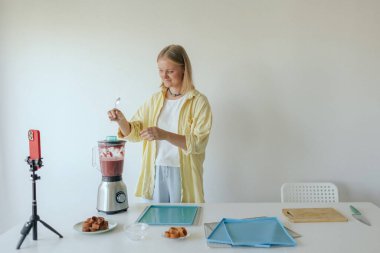 Orta yaşlı bir kadın ev yapımı meyve derisi hazırlıyor, sağlıklı atıştırmalıklar için mutfağında taze meyve dilimliyor. Organik ikramlar ve doğal yaşam üzerine bir serinin parçası. Kullanıcı kaynaklı içerik. Canlı yayın.