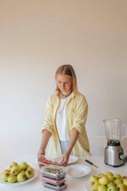 Beyaz kadın ev yapımı meyve derisi hazırlıyor, sağlıklı bir atıştırmalık için mutfağında taze meyve dilimliyor. Organik ikramlar ve doğal yaşam üzerine bir dizi..