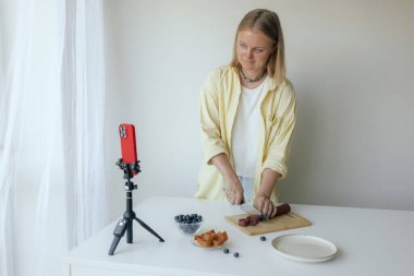 Orta yaşlı bir kadın ev yapımı meyve derisi hazırlıyor, sağlıklı bir atıştırmalık için mutfağında taze meyve dilimliyor. Organik ikramlar ve doğal yaşam üzerine bir serinin parçası. Kullanıcı tarafından oluşturulan içerik.