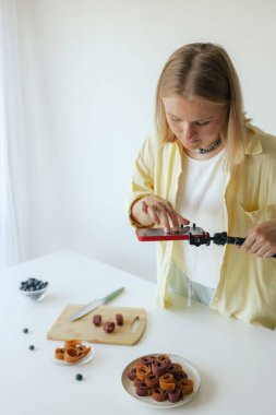 Orta yaşlı bir kadın ev yapımı meyve derisi hazırlıyor, sağlıklı bir atıştırmalık için mutfağında taze meyve dilimliyor. Organik ikramlar ve doğal yaşam üzerine bir serinin parçası. Kullanıcı tarafından oluşturulan içerik.