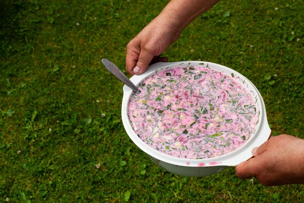 Cold beetroot in a huge bowl in the hands of an elderly woman — Stockfoto