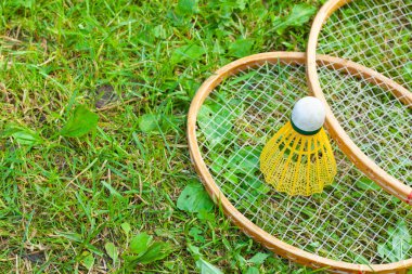 Raketler ve çimde badminton için bir servis horozu.