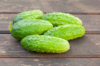 Tahta bir masada yeşil taze salatalık, kırsalda yaz hasadı.