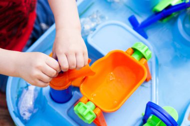 Çocuğun küçük elleri büyük oyuncak dilek balığı ve suda oynuyor.