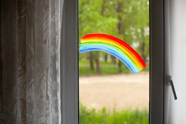 Close-up photo of painting rainbow on window. Rainbow painted with paints on glass for good mood