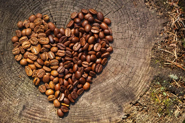 木の古いテクスチャの背景にコーヒー豆 オーガニックコーヒー 心の形をしたコーヒー豆 天然木は木の背景を伐採しました あなたのテキストの空きスペース メニューの空き容量 — ストック写真