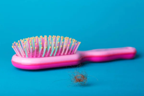 头发的问题 蓝色背景上的粉红色梳子和下拉头发 — 图库照片