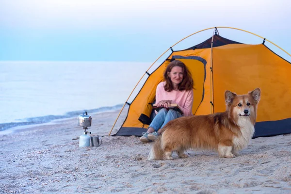 happy weekend by the sea - girl with a dog in a tent on the beach at dawn. Ukrainian landscape at the Sea of Azov, Ukrain