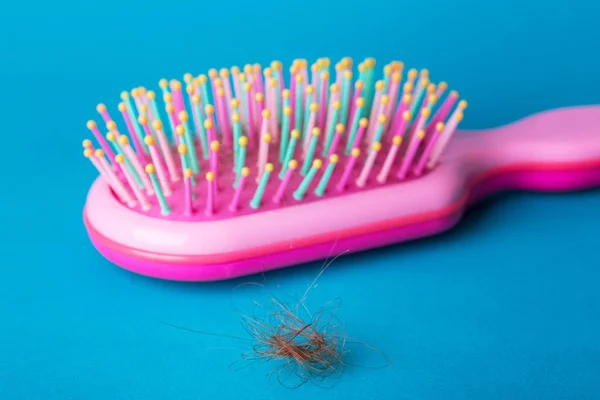 头发的问题 蓝色背景上的粉红色梳子和下拉头发 — 图库照片