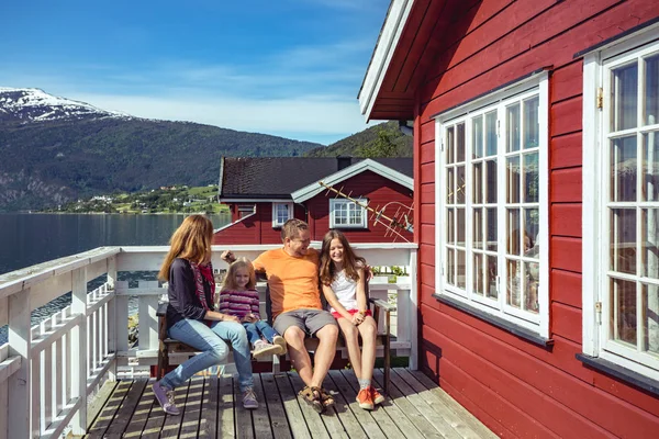 幸福的家庭微笑的父母和他们的两个女儿坐在传统的红色挪威房子附近 Norwa — 图库照片