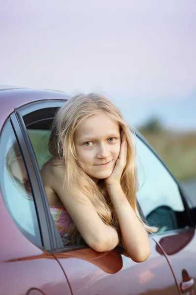 Glücklich Lächelndes Kleines Mädchen Blickt Aus Dem Autofenster Und Sonnenuntergang — Stockfoto