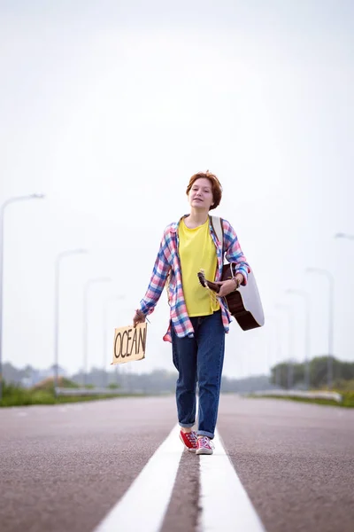 Giovane Ragazza Con Una Chitarra Che Arriva Lungo Strada Autostop — Foto Stock