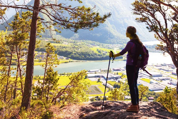 girl hiker with a backpack and trekking pole sitting and looking on Romsdalsfjorden and Andalsnes, Norwa