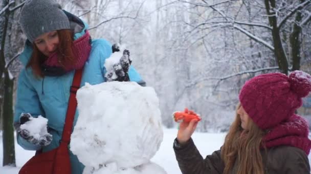 Moeder Haar Dochter Spelen Met Sneeuwpop Tijdens Sneeuw Vallen — Stockvideo