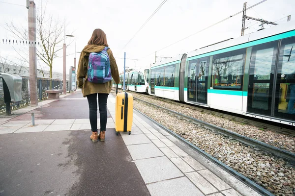 プラットホームと電車の待機で立っている女の子観光と バックパックと大きな黄色のスーツケース — ストック写真