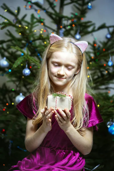 クリスマス トレの背景に手で新年の贈り物を保持して美しい笑っている女の子 — ストック写真