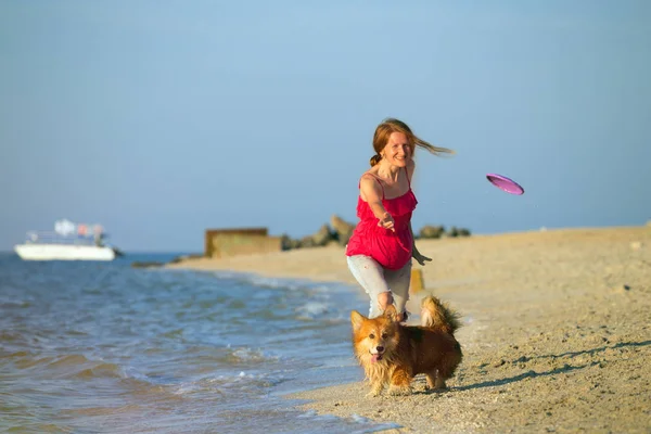 幸せな楽しい週末はビーチで犬とフリスビーで遊ぶ女の子 — ストック写真