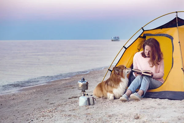 happy weekend by the sea - girl with a dog in a tent on the beach at dawn. Ukrainian landscape at the Sea of Azov, Ukrain