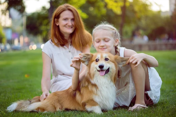 陽気な家族 ママと娘とコーギーのふわふわ座る芝生の上を笑顔 — ストック写真