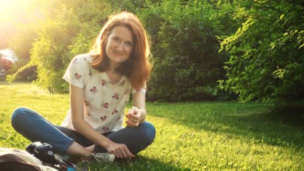 微笑的女孩坐在草地上在阳光明媚的夏夜 — 图库视频影像