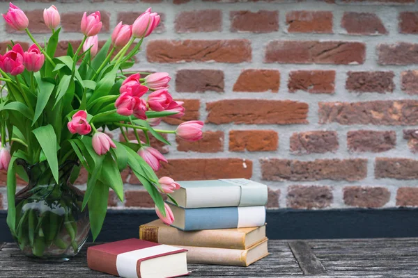 Mooie Roze Tulpen Een Vaas Boeken Tegen Een Bakstenen Muur — Stockfoto