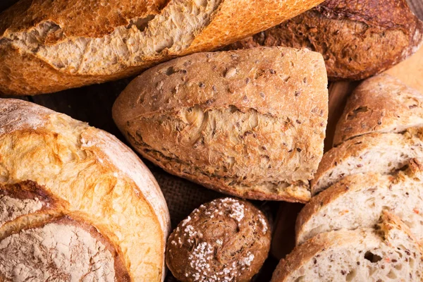 木片上不同的新鲜面包和面包 — 图库照片