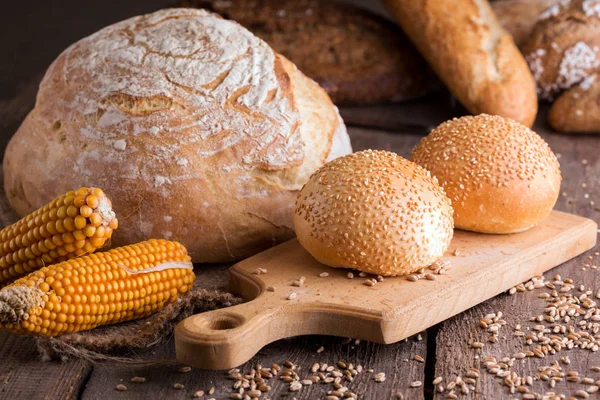Pão fresco e trigo na madeira — Fotografia de Stock