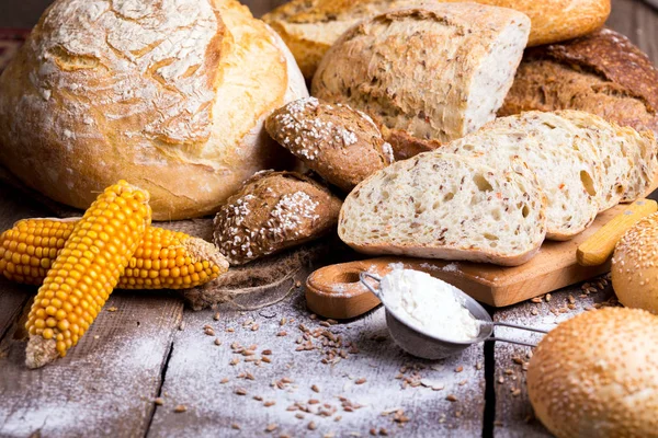 Pão fresco e trigo na madeira — Fotografia de Stock