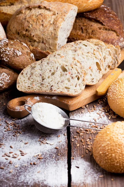 Pão fresco e trigo na madeira — Fotografia de Stock