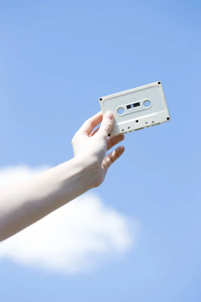 Cassette in the hands of the girl against the blue sky — Stock Photo, Image