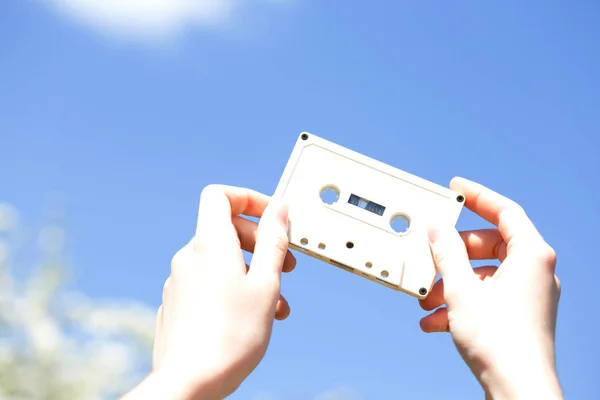 Cassette in the hands of the girl against the blue sky — Stock Photo, Image