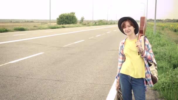 Chica Joven Con Una Guitarra Que Viene Largo Carretera Autoestop — Vídeos de Stock